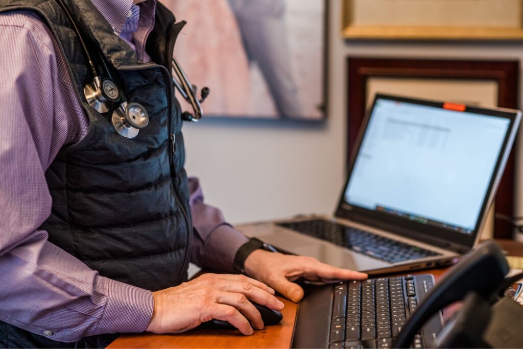 Doctor's hands typing on desktop computer at office desk