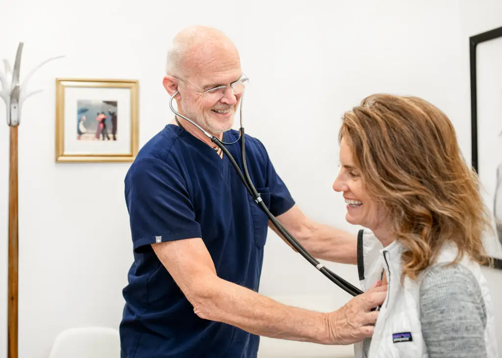 Dr. Duncan smiling while listening to a patient's breathing using a stethoscope