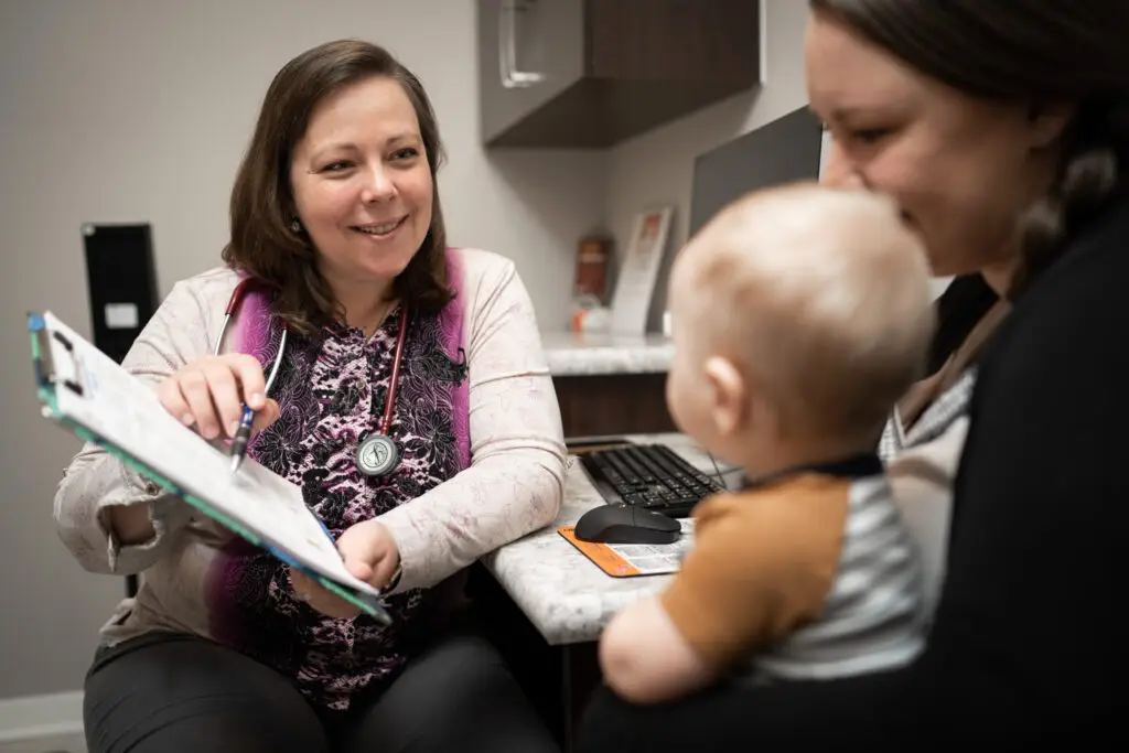 Doctor smiling while explaining chart to baby and mother