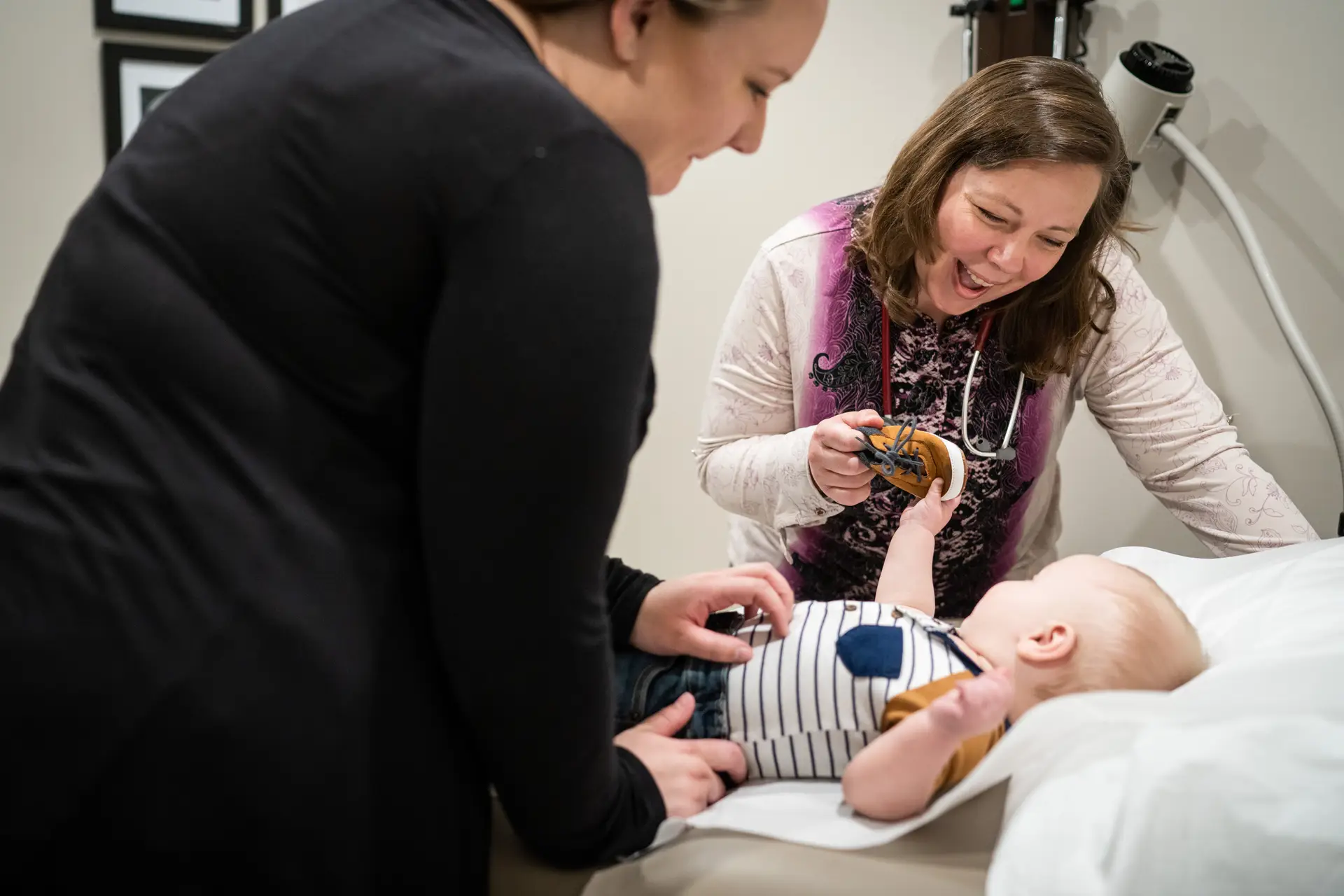 Doctor playing with a baby’s shoe during checkup